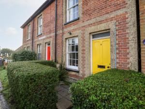 a yellow door on the side of a brick building at 3 Albion Cottages in Southwold