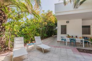 un patio con sillas, una mesa y una mesa con sillas en Villa Nami a 50mt dalla spiaggia, en Torre Santa Sabina