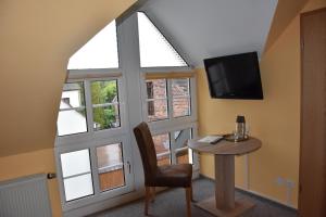 Zimmer mit einem Tisch, einem TV und einem Fenster in der Unterkunft Hotel La-Pergola in Kolkwitz