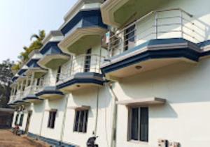 - un grand bâtiment blanc avec des balcons bleus dans l'établissement Hotel R.K.Palace Jharkhand, à Pākaur