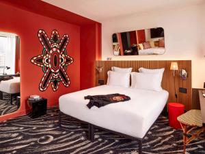 um quarto com uma cama branca e uma parede vermelha em Mama Shelter Paris La Défense em Puteaux