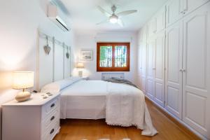 a white bedroom with a bed and a window at Villa Can Raco Ibiza in Sant Rafael de Sa Creu