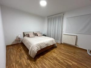 Habitación blanca con cama y suelo de madera. en 20 Pasos, en Tudela