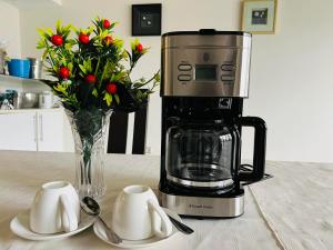 a coffee maker and a vase of flowers on a table at TRMOTEL in Matola