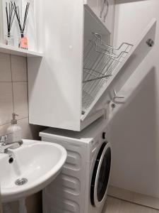 een witte wasmachine in een badkamer naast een wastafel bij Bright Prishtina City Apartment in Pristina