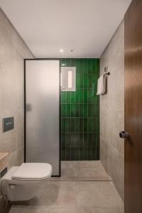 a bathroom with a toilet and a shower with green tiles at Livingville Nine in Cairo