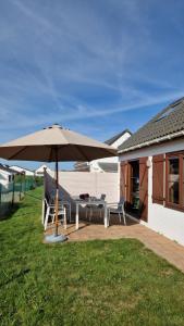eine Terrasse mit einem Tisch und einem Sonnenschirm in der Unterkunft Vissershuisje 89 te Wenduine in Wenduine