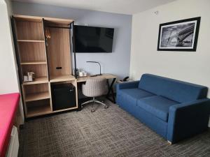 a living room with a blue couch and a desk at Eva Hotel Buffalo Airport, BW Signature Collection in Buffalo