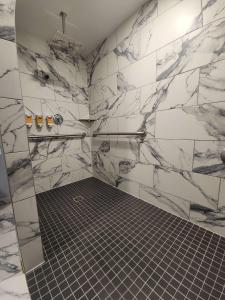 a bathroom with white marble walls and a shower at Eva Hotel Buffalo Airport, BW Signature Collection in Buffalo