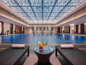 a pool with a table in front of a swimming pool at Pullman Quanzhou Shuitou in Quanzhou