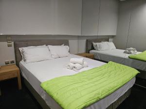 dwa łóżka w pokoju z zieloną pościelą w obiekcie Feevos w Pireusie