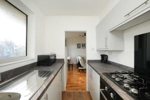 a kitchen with a counter top and a stove at Modern Two Bedroom Flat with Free Parking Near Heathrow in Feltham