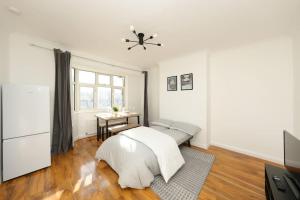 Dormitorio blanco con cama y mesa en Modern Two Bedroom Flat with Free Parking Near Heathrow en Feltham
