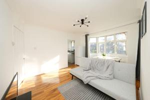 a living room with a white couch and a window at Modern Two Bedroom Flat with Free Parking Near Heathrow in Feltham