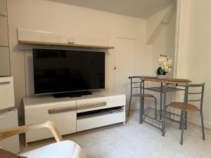 a living room with a flat screen tv and a table at Le Bois des Sources in Saint-Marcel