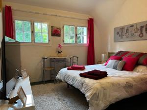 una camera da letto con un grande letto con cuscini rossi di Le Bois des Sources a Saint-Marcel