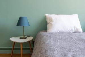 a bed with a white pillow and a lamp on a table at Chez Magali in Rouen