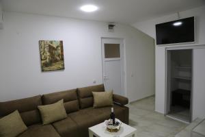 Studio T&M, sa parkingom في Obrenovac: غرفة معيشة مع أريكة بنية وطاولة