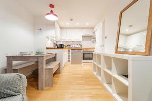 a kitchen with white cabinets and a table and a mirror at Modern flat in PRIME LOCATION near Shoreditch & Brick lane in London