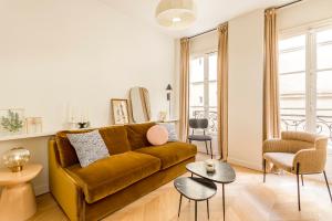 een woonkamer met een bruine bank en een stoel bij Lune Montorgueil in Parijs