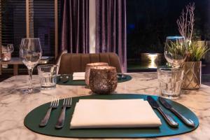 Asperion Hillside Hotel في غيلدفورد: طاولة وصحون خضراء وشوك ومناديل
