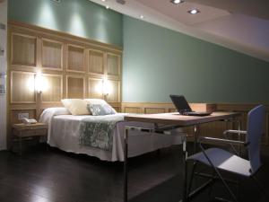 a bedroom with a bed and a desk with a laptop on it at Hotel Vía Gótica in Burgos
