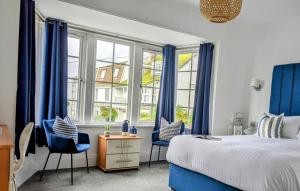sypialnia z niebieskimi zasłonami oraz łóżkiem i krzesłami w obiekcie The Westcott by the Sea - Just for Adults w mieście Falmouth