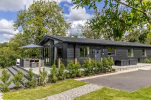 a black house with a garden in front of it at Maple Lodge, 20 Roadford Lake Lodges in Lifton