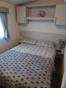 a bedroom with a bed with a plaid comforter at 8 berth caravan Turnberry Holiday Park in Turnberry