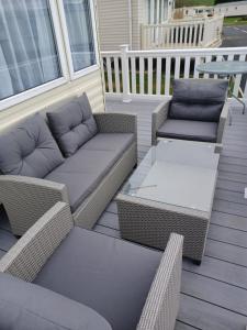a patio with wicker chairs and couches on a porch at 8 berth caravan Turnberry Holiday Park in Turnberry
