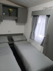 two beds in a small room with a window at 8 berth caravan Turnberry Holiday Park in Turnberry