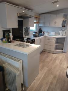 a kitchen with white cabinets and a white counter top at 8 berth caravan Turnberry Holiday Park in Turnberry