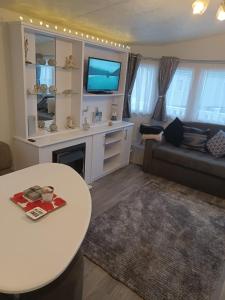 a living room with a white table and a tv at 8 berth caravan Turnberry Holiday Park in Turnberry