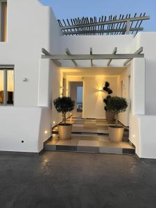 a hallway with potted trees in a white building at Aegean Diamonds Luxury Suites in Monolithos