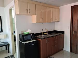 a kitchen with brown cabinets and a black refrigerator at 3N Palm Tree Villas in Manila