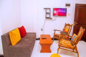 a living room with a couch and chairs and a tv at City Beach Apartment in Bentota