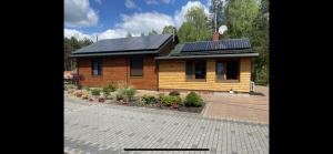 a small wooden house with solar panels on the roof at Leśna Polana- Kompleks Domków Mieszkalnych 