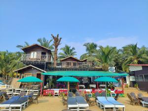 un grupo de sillas y sombrillas en una playa en Roundcube Beach Bungalows Patnem, en Patnem