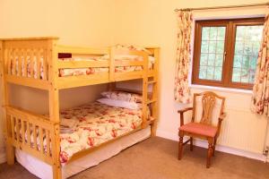 サウス・モルトンにあるWest Down Farmhouseのベッドルーム1室(二段ベッド2台、椅子付)