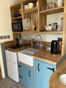 a kitchen with blue cabinets and a sink at Close to Nature Easy to Find shepherd's hut in North Molton