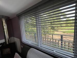 a bedroom with a large window with blinds at Close to Nature Hedgehogs Lodge in South Molton