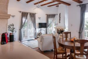 ein Wohnzimmer mit einem Tisch und Stühlen sowie einem TV in der Unterkunft Ca Adelfa in Muntanya la Sella
