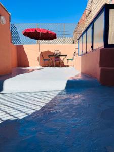 patio con tavolo, ombrellone e acqua di Dar Beldi a Marrakech