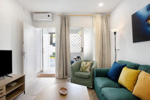 ein Wohnzimmer mit einem grünen Sofa und einem TV in der Unterkunft Apartamento El Músico in Barbate