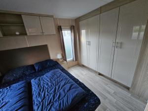 a bedroom with a blue bed and white cabinets at ZP 508 - Camping de Zandput in Vrouwenpolder