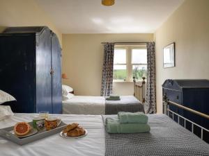1 dormitorio con 2 camas y una bandeja de comida en la cama en Stable Yard Cottage en Greenlaw