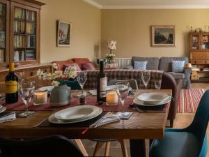 Stable Yard Cottage في Greenlaw: طاولة غرفة الطعام مع زجاجات النبيذ والاكواب