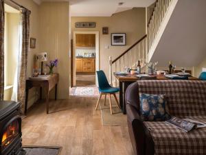 a living room with a couch and a table and a fireplace at Stable Yard Cottage in Greenlaw