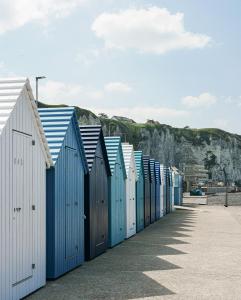 een rij blauwe strandhutten op het strand bij EGG HOTEL - HOTEL LES GENS DE MER Dieppe in Dieppe