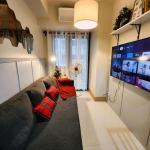 un soggiorno con un divano e una grande TV di My Humble Abode at Shore 3 a Manila